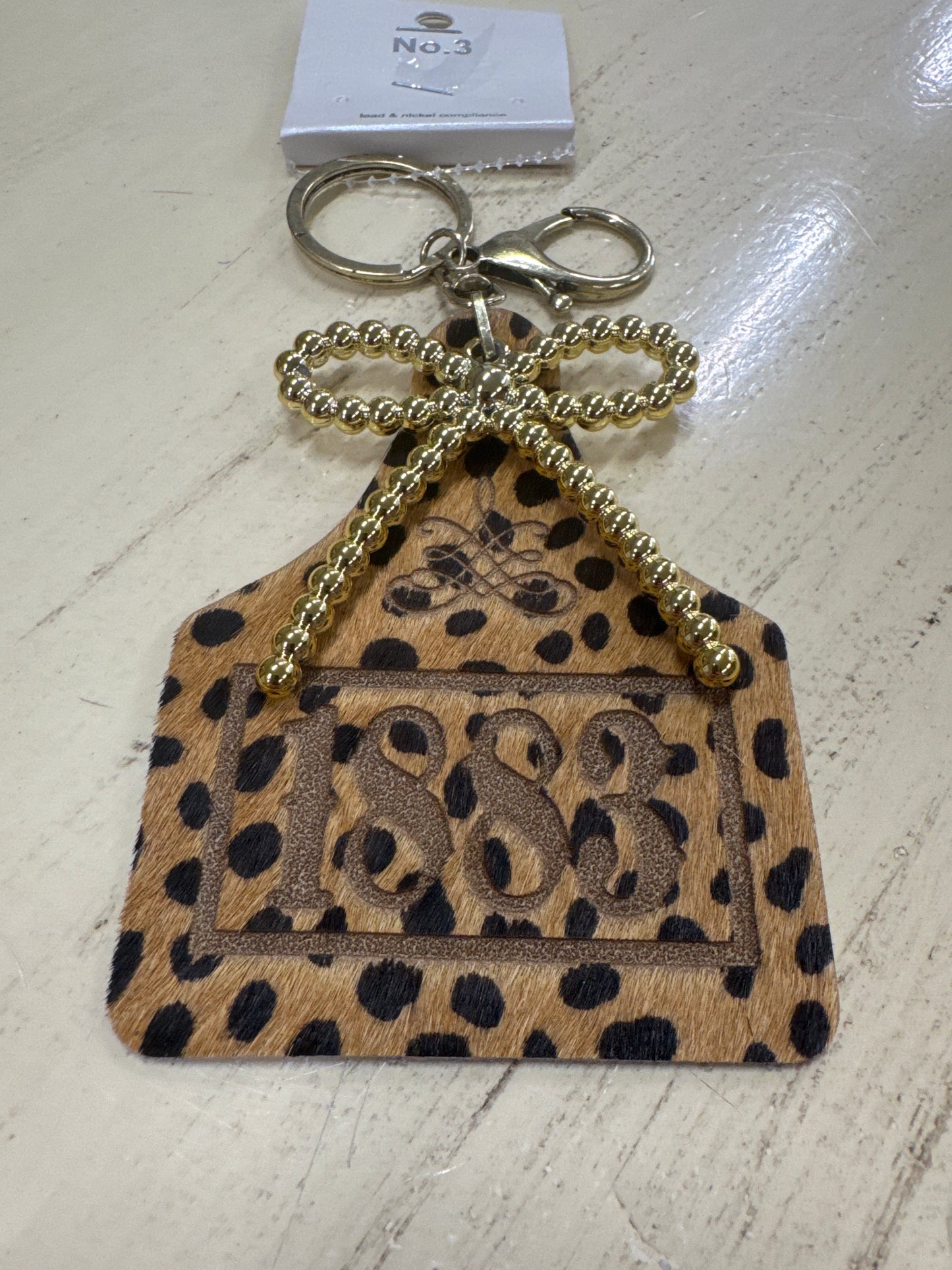 1883 COW EAR TAG KEY RING W/ GOLD BOW