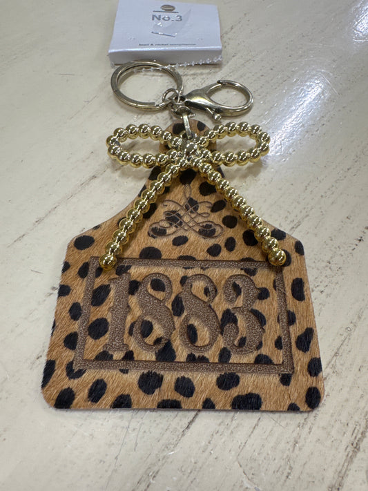 1883 COW EAR TAG KEY RING W/ GOLD BOW
